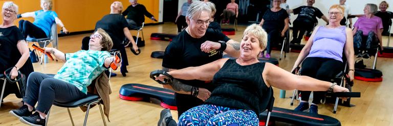 Group of adults indoors doing chair exercises