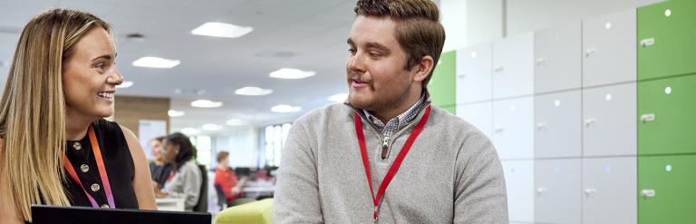 Two adults sitting talking with one holding a laptop