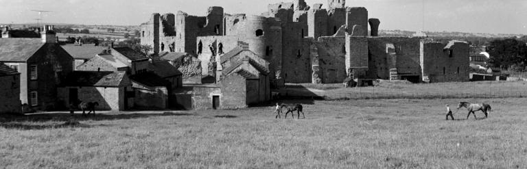 Black and white photo of three horses with their handlers at the stables at the Castle at Middleham