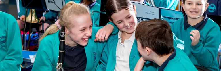 Group of children from the school band with their instruments talking and smiling together