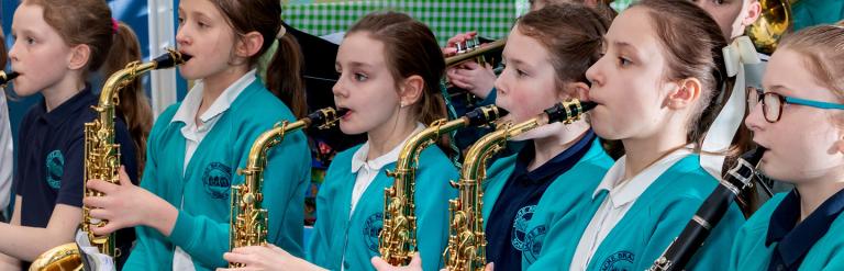 School children in their school uniform standing playing their musical instruments