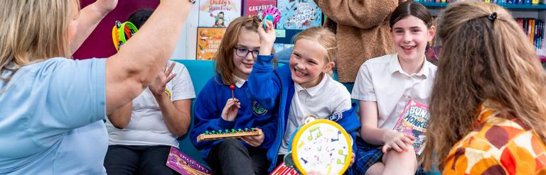 Group of children sitting with adults playing musical instruments