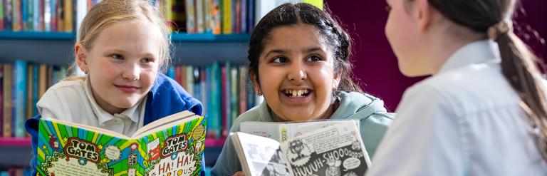 Three school children holding books smiling