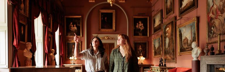 Two adults walking inside Castle Howard looking at all the art and sculpture collection. Photo by Charlie Kirkpatrick